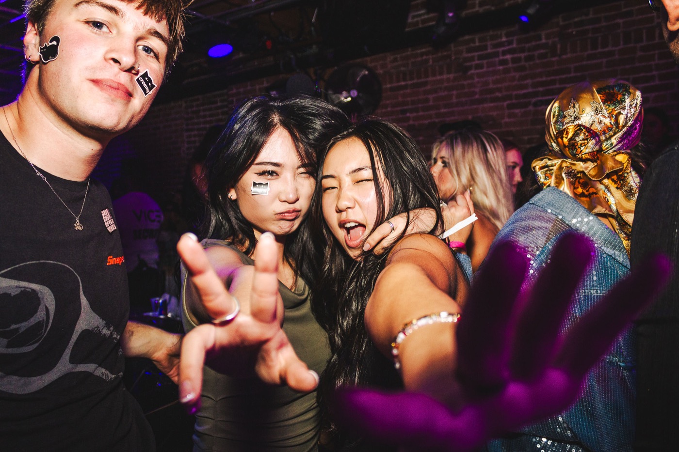 Partygoers with Boba After Hours stickers on their faces