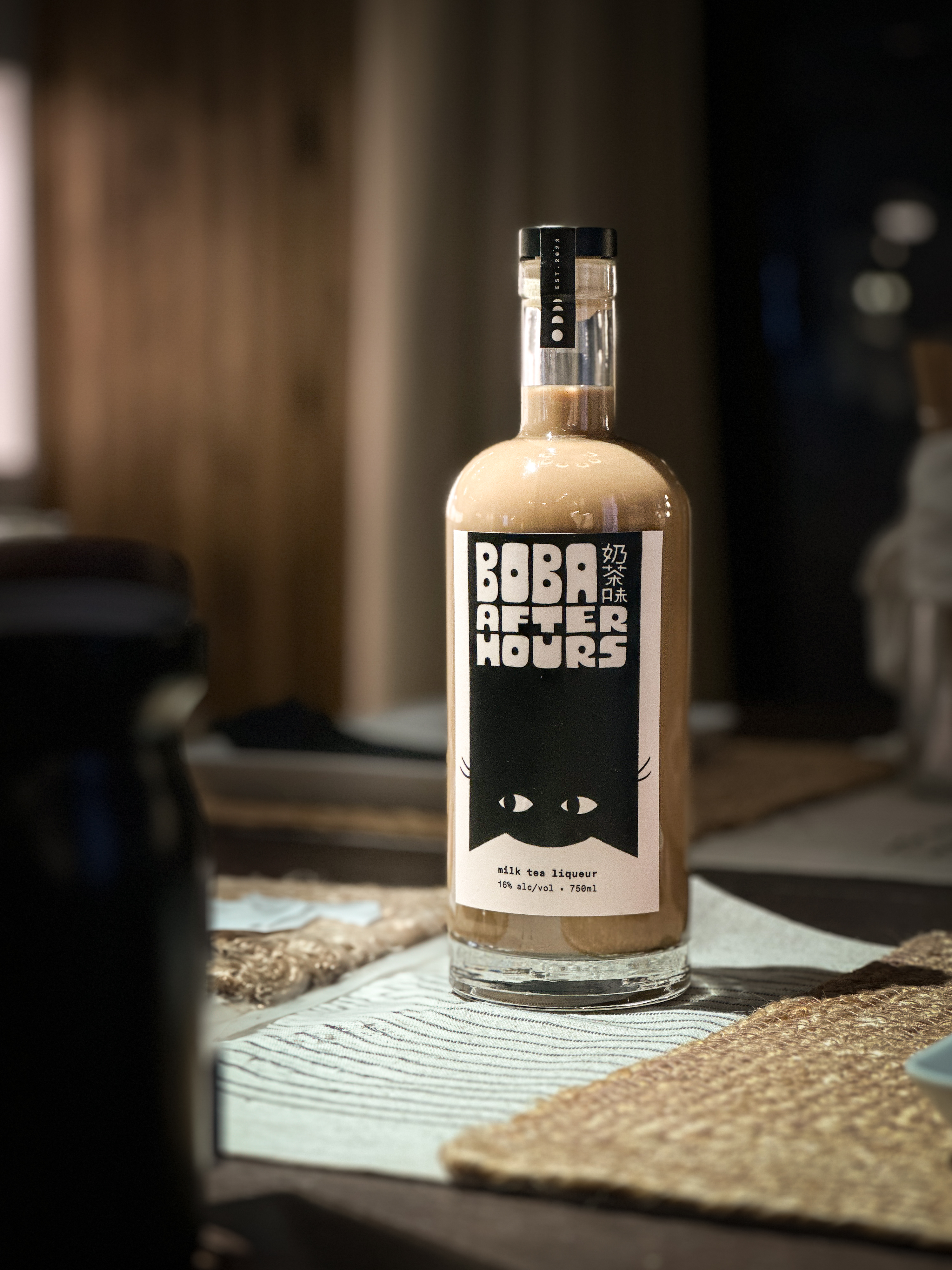 A bottle of Boba After Hours milk tea liqueur in warm, low light